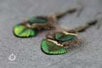 Plumes de paon vertes et bleues sur boucles d’oreilles, détail des tiges.