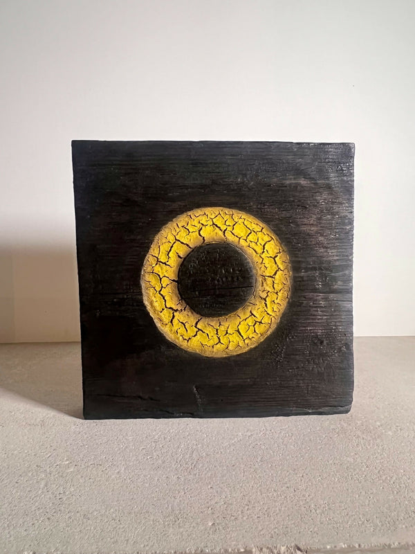 Panneau de sculpture en bois sombre avec anneau jaune et trou central noir