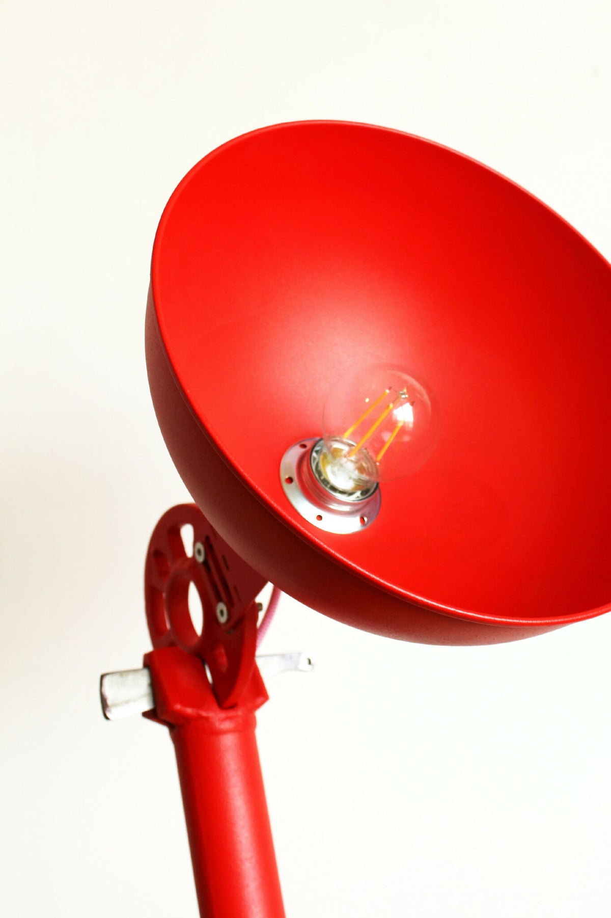 Abat-jour conique rouge avec ampoule visible et support métallique sur bras