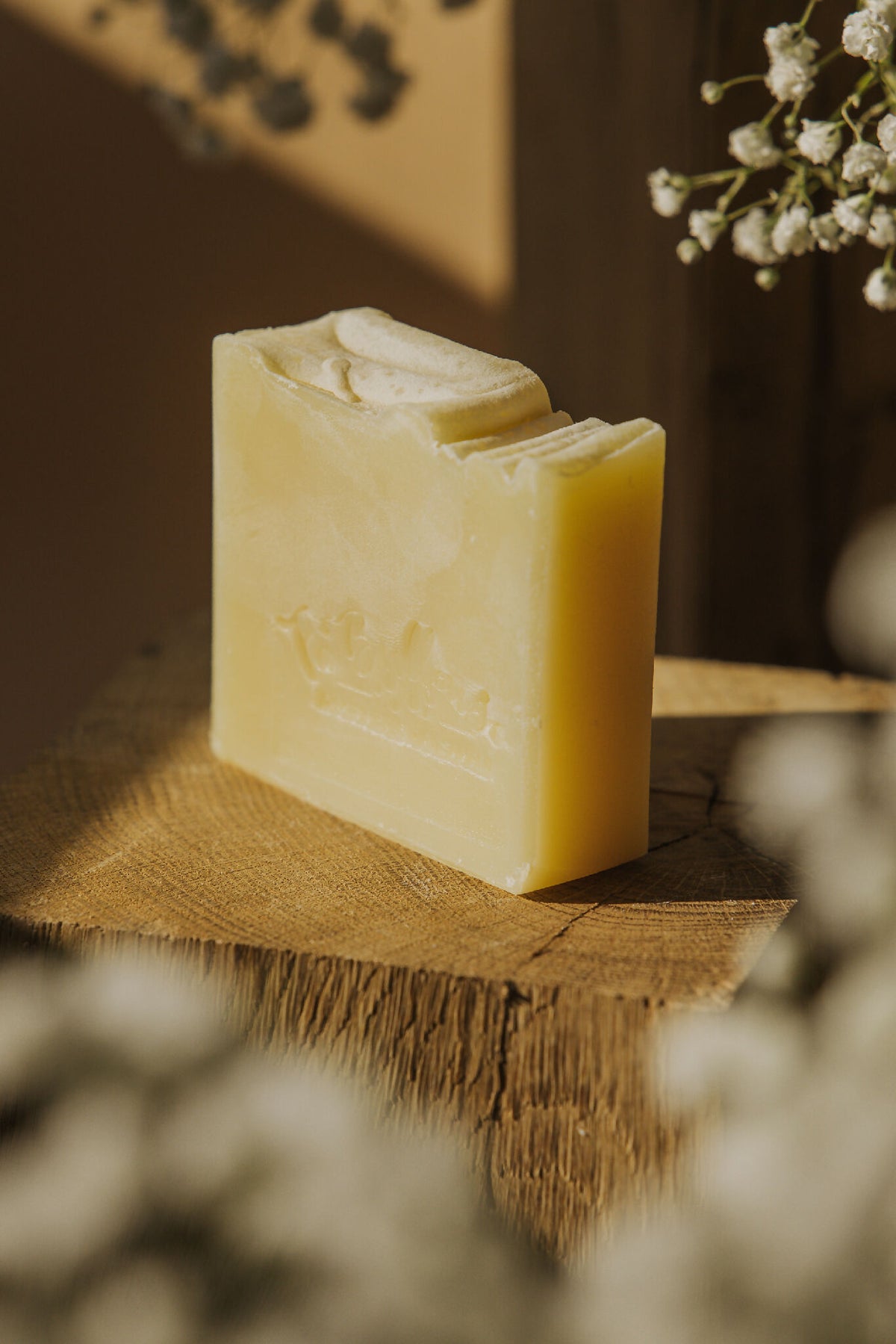 Savon Fantastique au calendula, barre crème vue de trois quarts sur un support en bois.