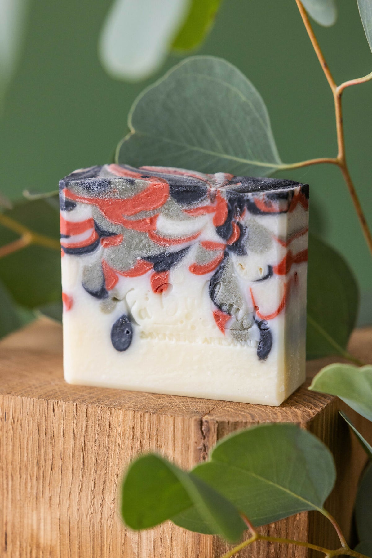 Savon solide rectangulaire au charbon actif, base jaune pâle, dessus marbré noir et rouge.
