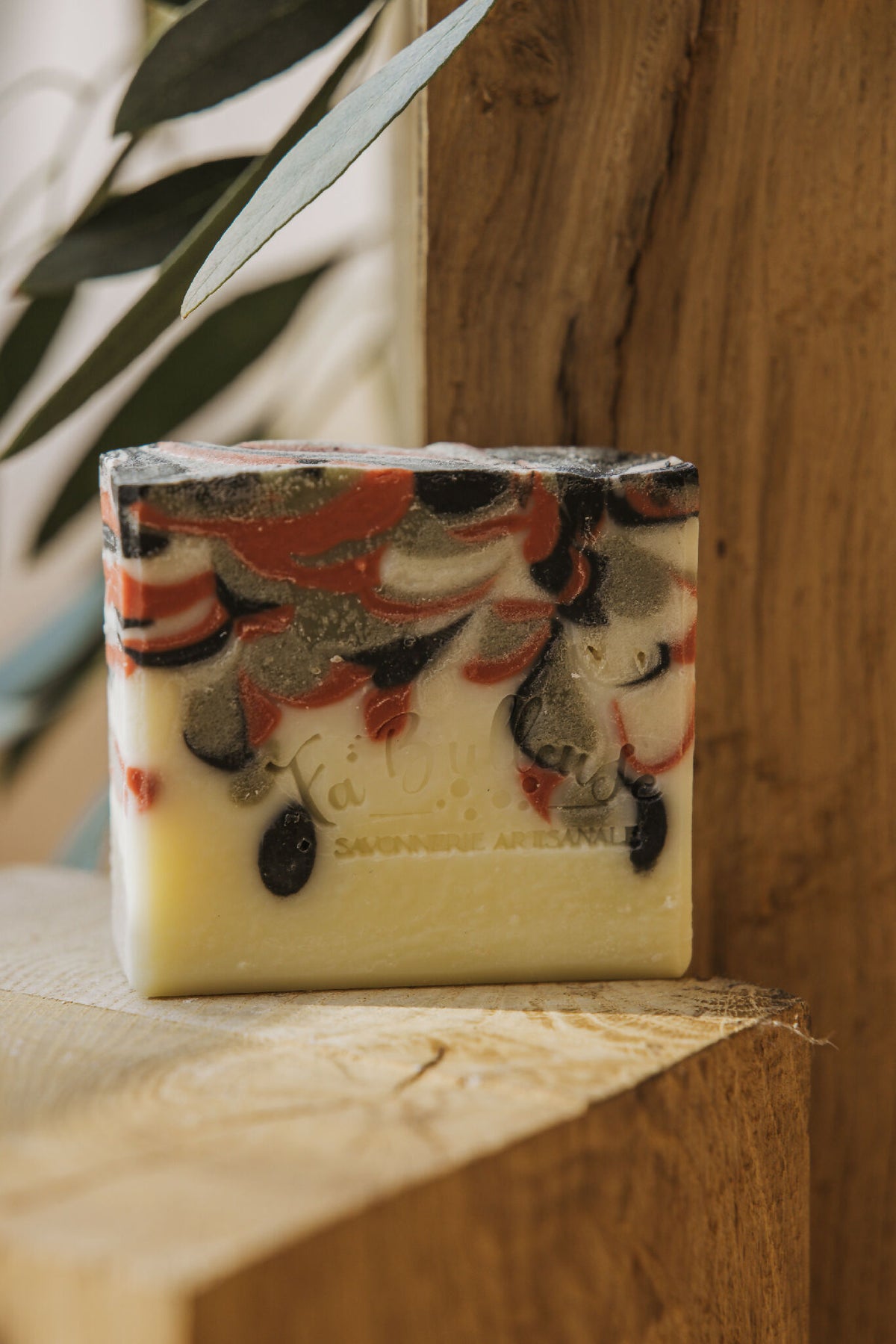 Savon solide rectangulaire, dessus marbré noir et rouge, bloc jaune pâle.