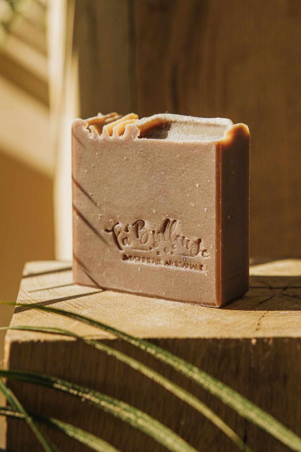 Savon au cacao Fameux en barre rectangulaire brun clair sur plateau en bois