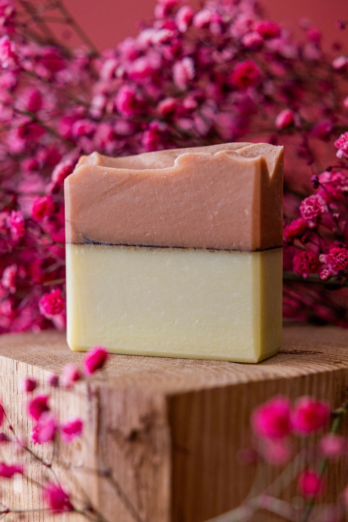 Savon en barre bicolore argile rouge et curcuma, tranche visible sur plateau en bois.