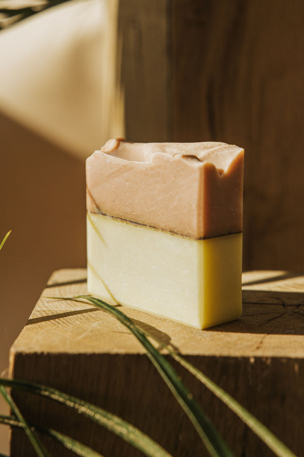 Savon en barre bicolore sur trépied en bois, vue de côté, surface lisse.