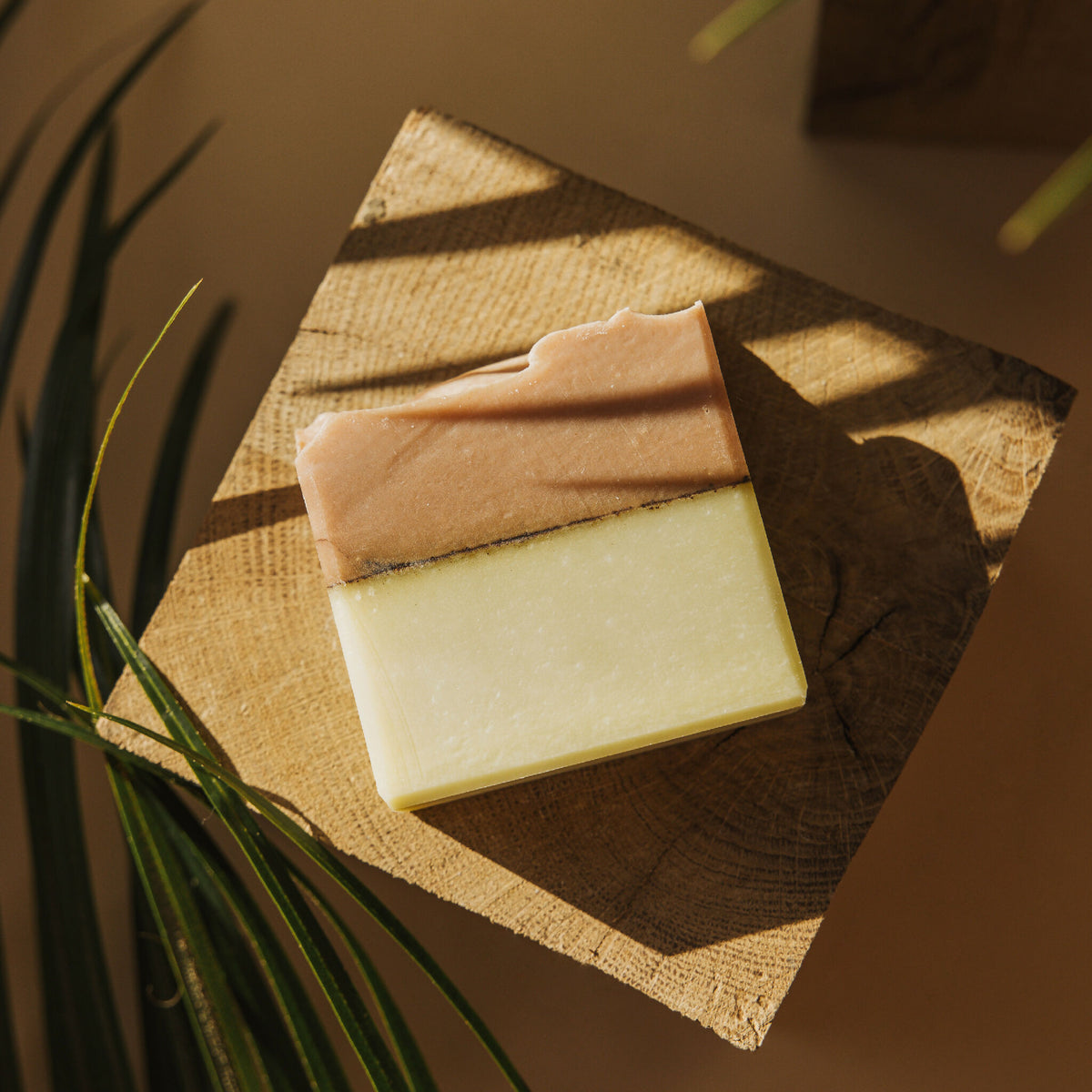 Savon en barre bicolore posé sur serviette en tissu beige, angles taillés.