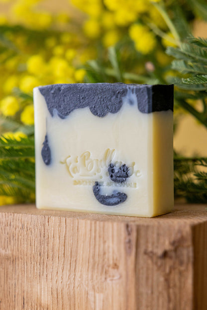 Savon au patchouli et charbon végétal, bloc blanc avec marbrures bleu foncé.