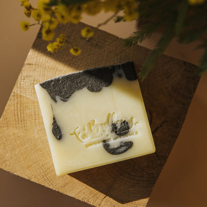 Savon au patchouli et charbon végétal, cube blanc aux traces de charbon sombre.