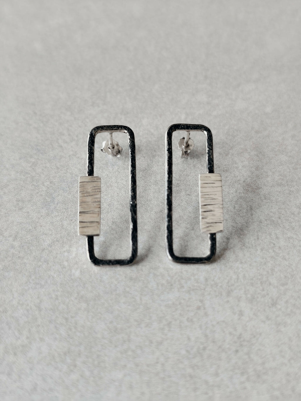 Boucles d’oreilles rectangulaires métal argenté, contours foncés et plaque texturée