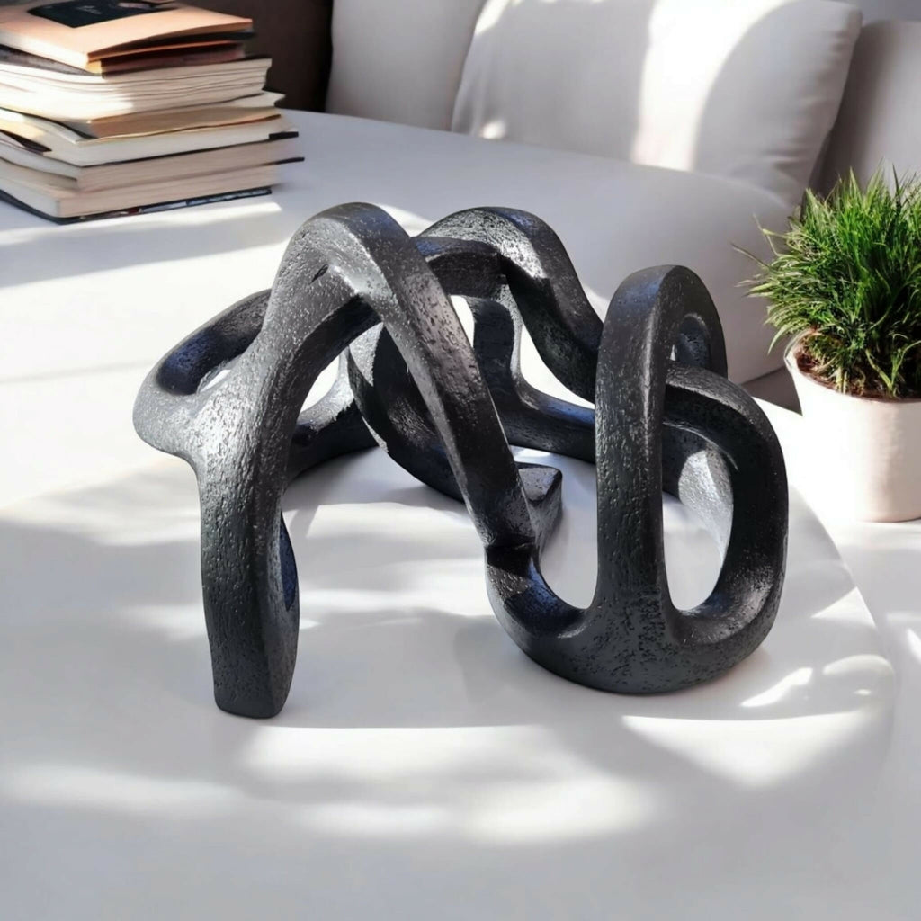 Sculpture abstraite en argile sombre, vue en perspective des anneaux entrelacés.