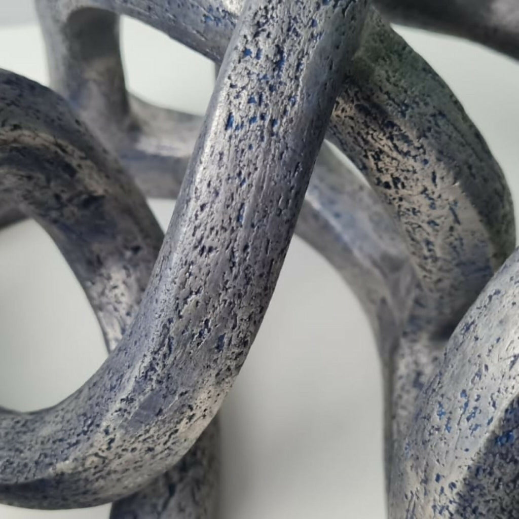 Détail de la sculpture abstraite : surface granuleuse gris bleuté, taches sombres.