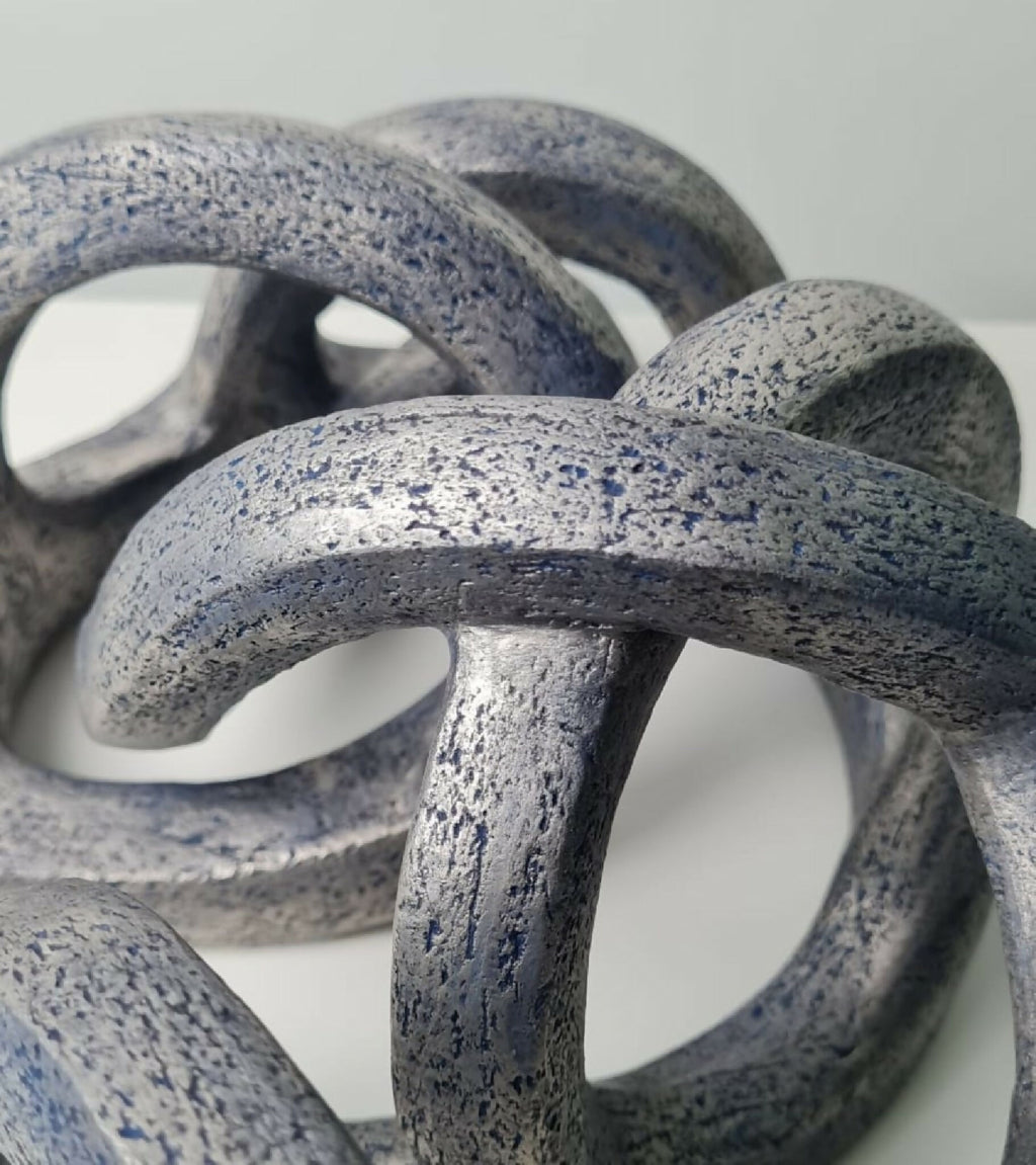 Courbes enchevêtrées de la sculpture abstraite, texture granuleuse avec points bleus.