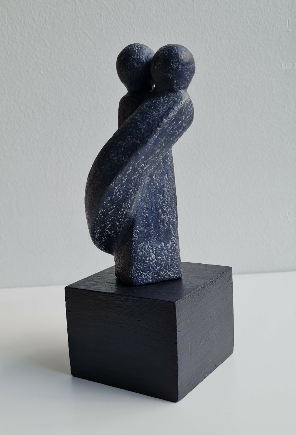 Sculpture couple sur socle noir cubique, silhouettes en résine bleue texturée