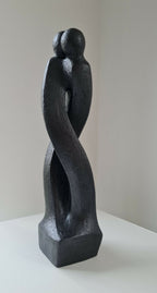 Sculpture en argile sombre de deux corps enlacés, posture debout