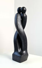 Sculpture en argile sombre de deux personnages enlacés, vue 3/4 arrière