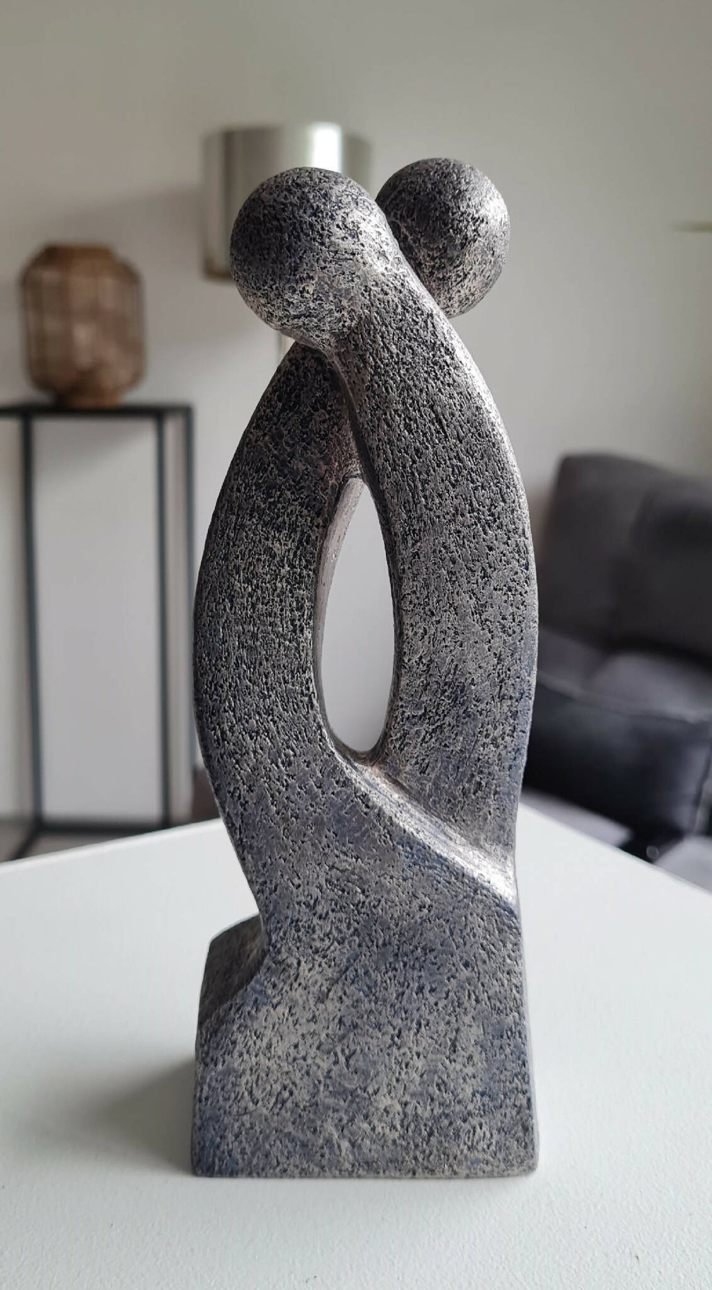 Sculpture en argile grise, silhouette en double courbe avec ouverture ovale et base droite.