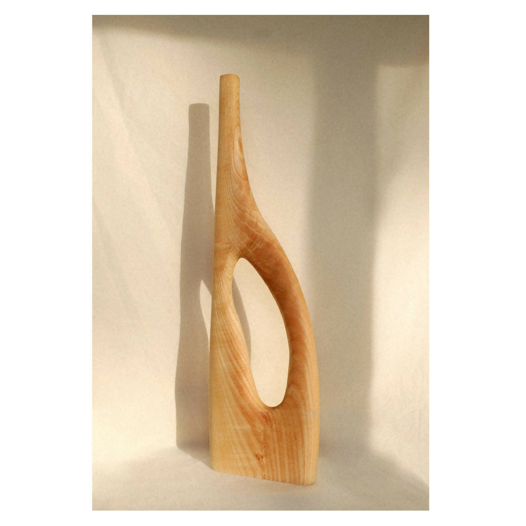 Objet décoratif en bois blond avec forme incurvée et ouverture en U.
