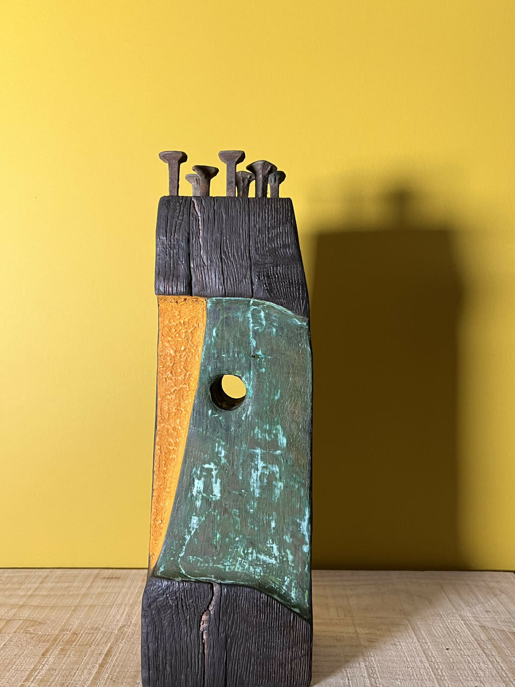 Totem II en bois patiné, panneau vert-bleu et orange, crochets métalliques en haut.