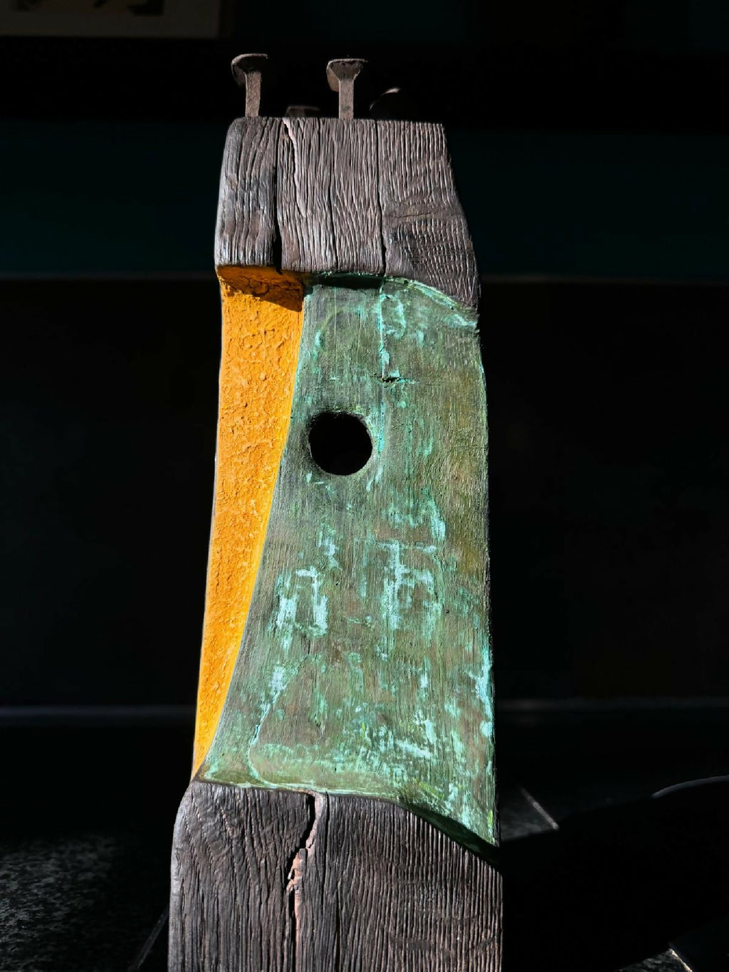 Totem II en bois, panneaux orange et vert-bleu, trou circulaire au centre.
