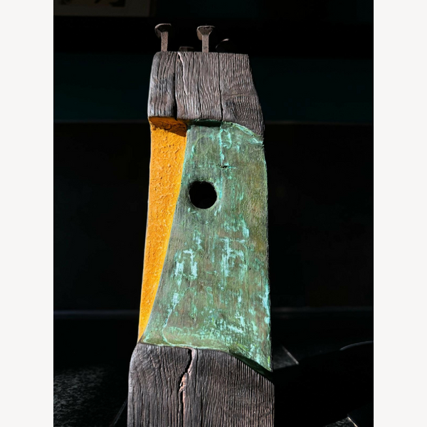 Statue totem décorative en métal patiné, colonne empilée, trou circulaire au centre.
