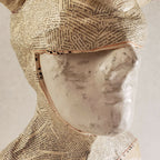 Buste sculpté: gros plan du visage masqué en papier texturé beige, détails et bords visibles