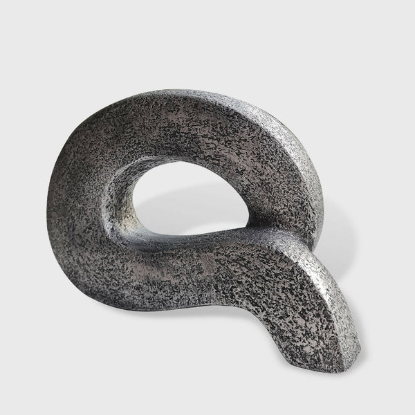 Sculpture abstraite en pierre sombre à forme de boucle, ouverture ovale