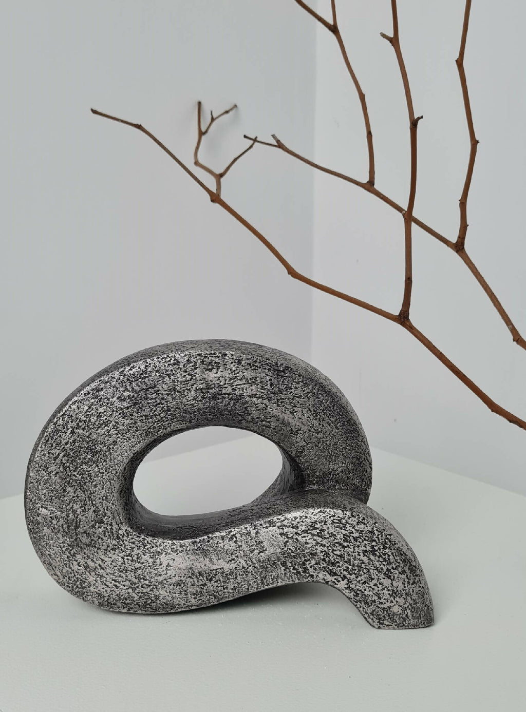Sculpture abstraite en pierre sombre avec boucle ovale, vue de face