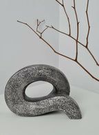 Sculpture abstraite en pierre sombre avec boucle ovale, vue de face