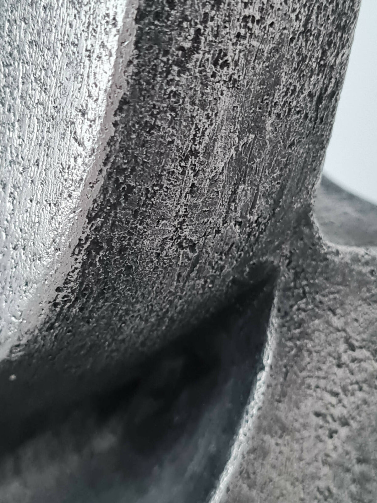 Détail de sculpture : surface métallique texturée gris foncé avec reliefs