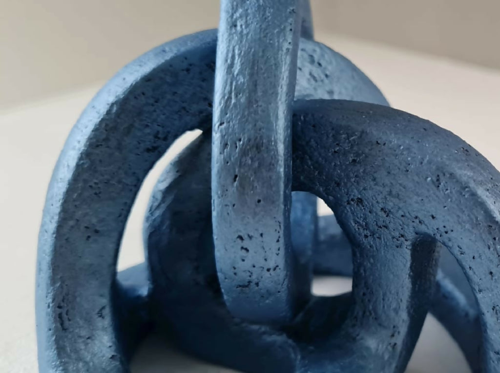 Sculpture abstraite bleue, vue rapprochée des anneaux ajourés et tige verticale.