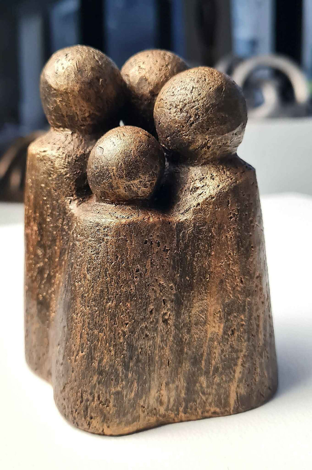 Sculpture contemporaine en bronze patiné, quatre têtes arrondies, vue de face.