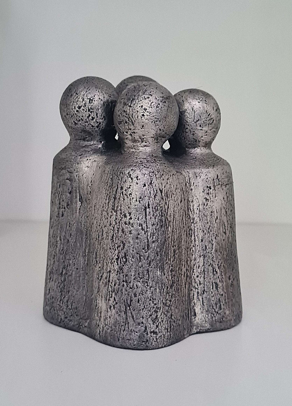 Sculpture contemporaine en gris foncé, trois personnages ronds sur une base