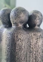 Vue rapprochée de la sculpture : textures granuleuses et trois têtes rondes
