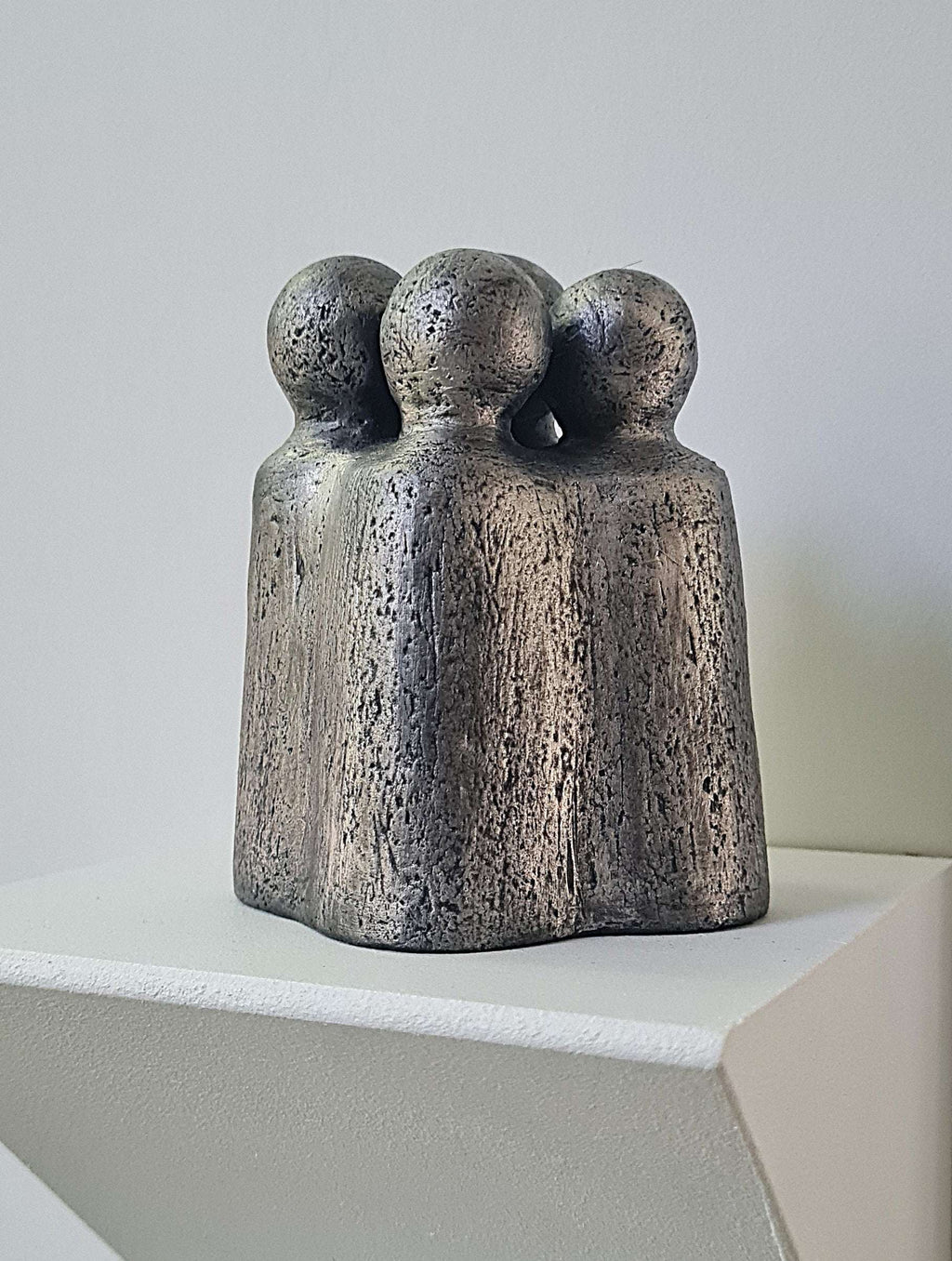 Sculpture en métal gris foncé, trois figures assemblées debout sur socle