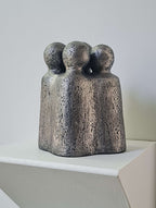 Sculpture en métal gris foncé, trois figures assemblées debout sur socle