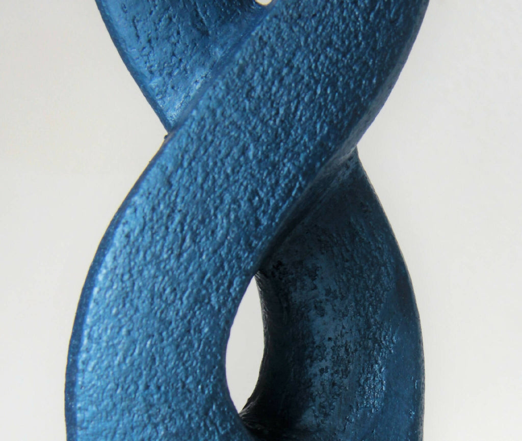 Gros plan sur sculpture bleue texturée, courbe en X avec ouverture sombre.