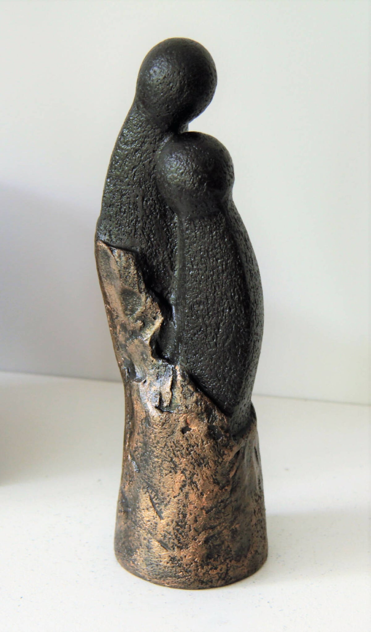 Sculpture couple en figurine : vue arrière, silhouettes noires et dorées, socle arrondi.