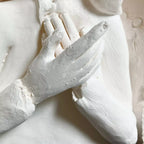 Détail sculpture: femme blanche, mains et oiseau en relief, texture piquée
