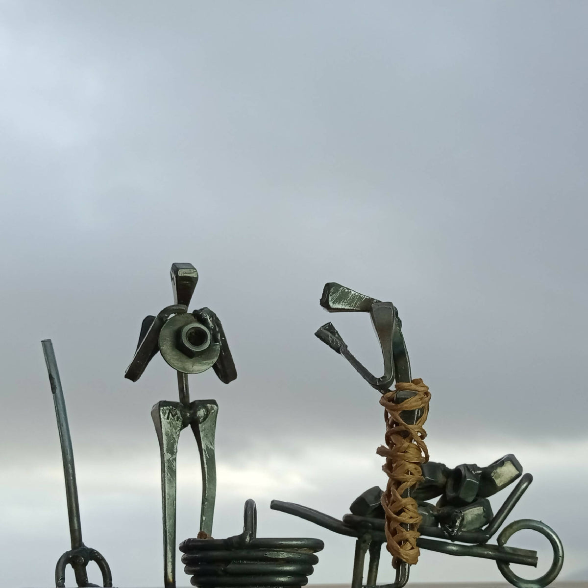 Sculpture métal patiné : personnage debout et musicien à genoux, sur socle.