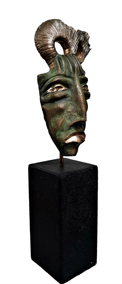 Masque sculpté bronze vert sur socle noir, vue de profil