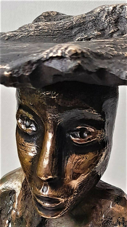 Sculpture de visage en métal noir et doré, regard détaillé et coiffe en relief