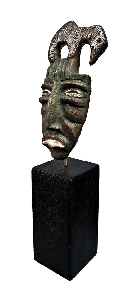 Masque sculpté bronze vert sur socle noir, visage en gros plan