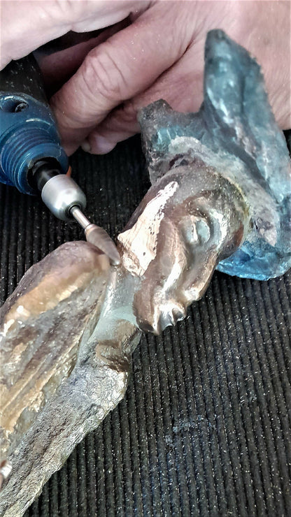 Retouche de sculpture : outil et main, détail en métal vert et doré