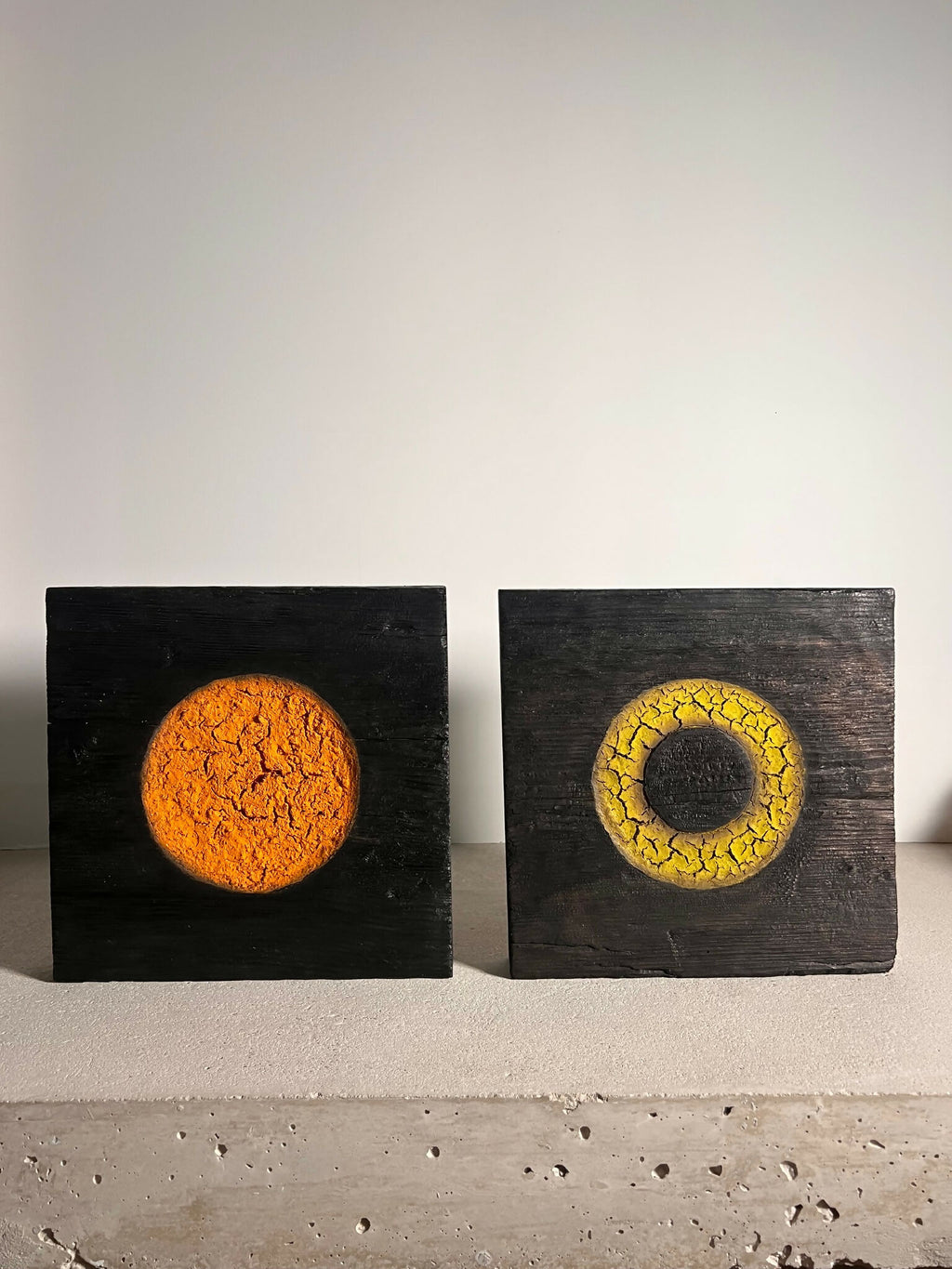 Deux panneaux de sculpture en bois sombres : disque orange et anneau jaune