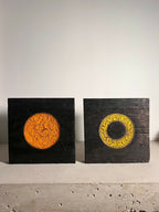 Deux panneaux de sculpture en bois sombres : disque orange et anneau jaune