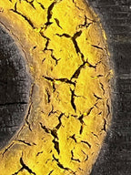 Gros plan sur sculpture en bois : surface jaune fissurée et relief sombre