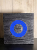 Panneau de sculpture en bois foncé avec cercle bleu au centre