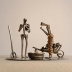Sculpture décorative en métal, deux personnages mécaniques sur socle circulaire.