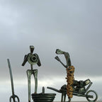 Sculpture métal patiné : personnage debout et musicien à genoux, sur socle.