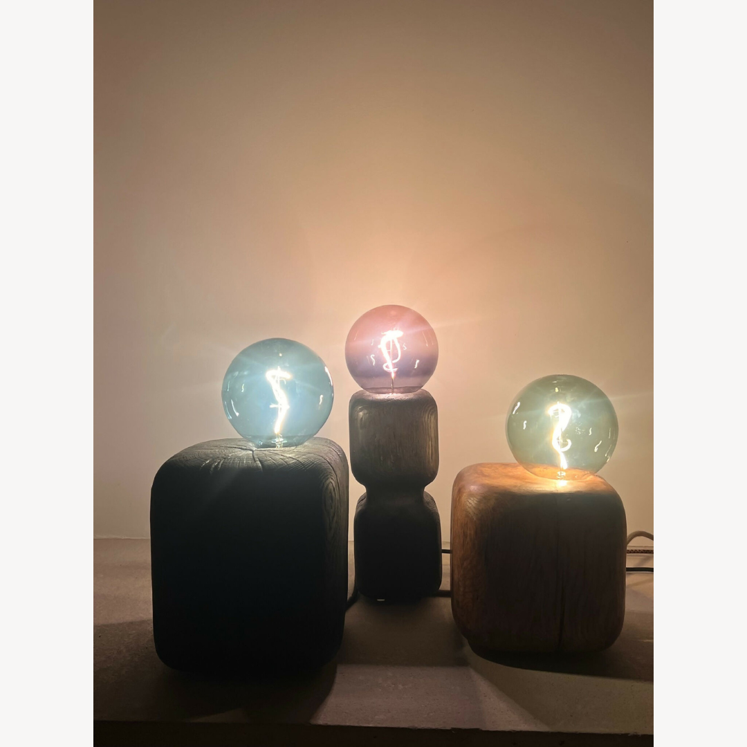 Trois sculptures lumineuses alignées : ampoules sphériques sur bases cubiques.